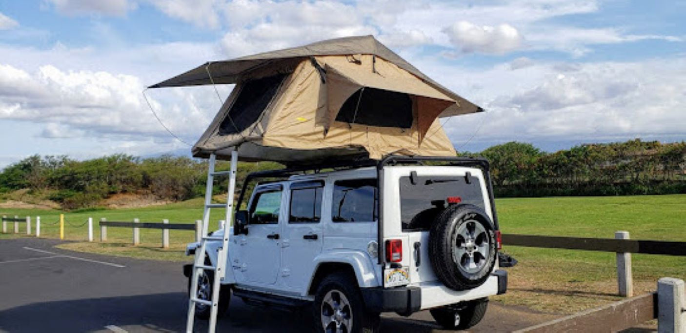 White Jeep Wrangler with a deployed rooftop tent for camping