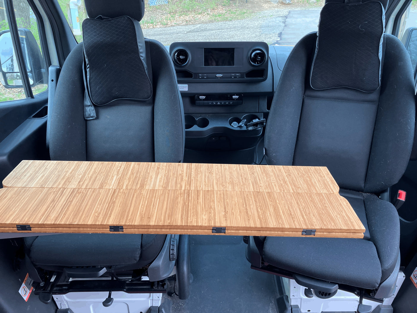 RV rental interior: A wooden table set up between the front driver and passenger seats, creating a compact dining or workspace.