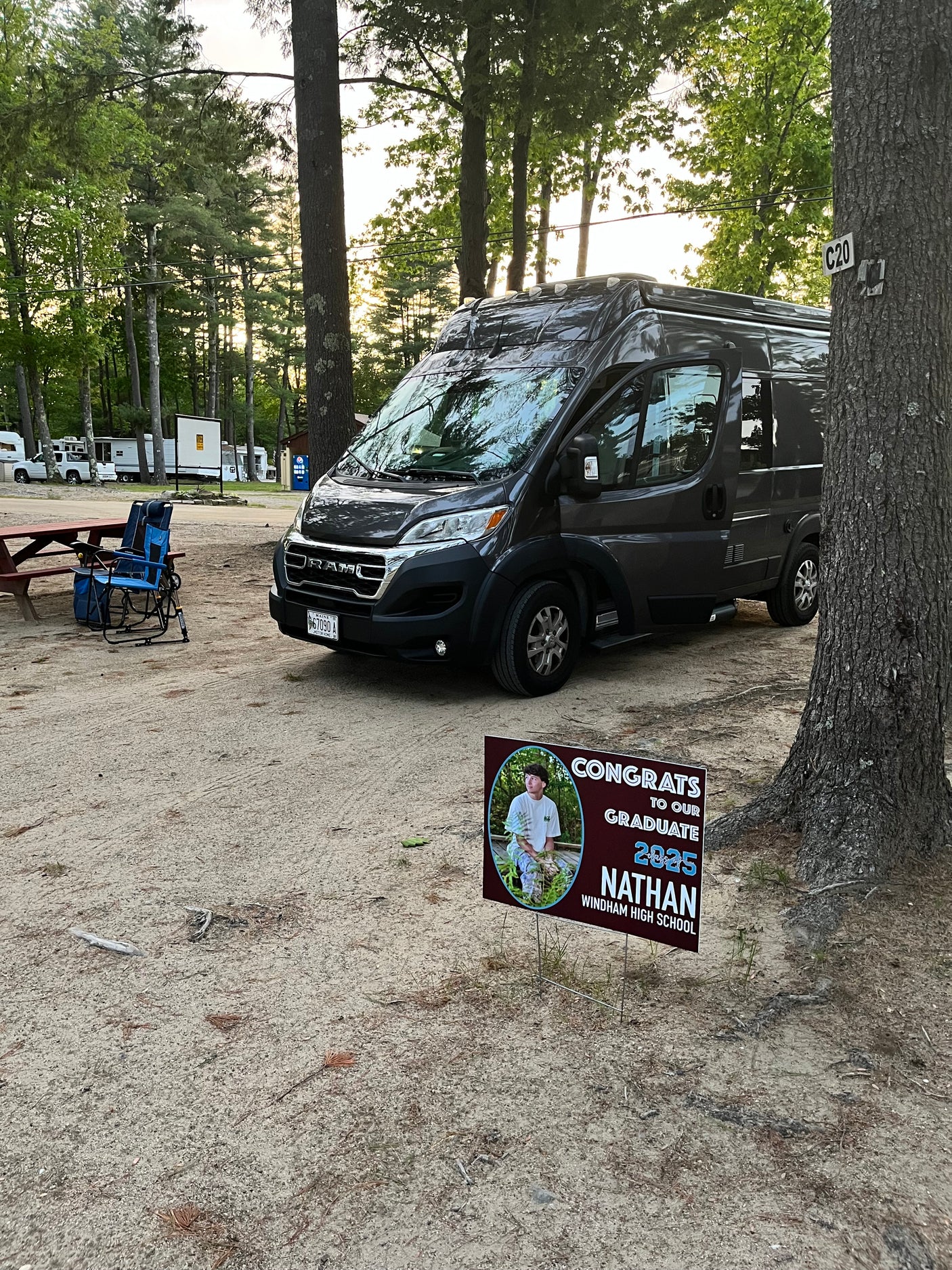 Dark grey RV rental at C20 campsite, next to a picnic table. A yard sign congratulates Nathan, Windham High School Class of 2025.