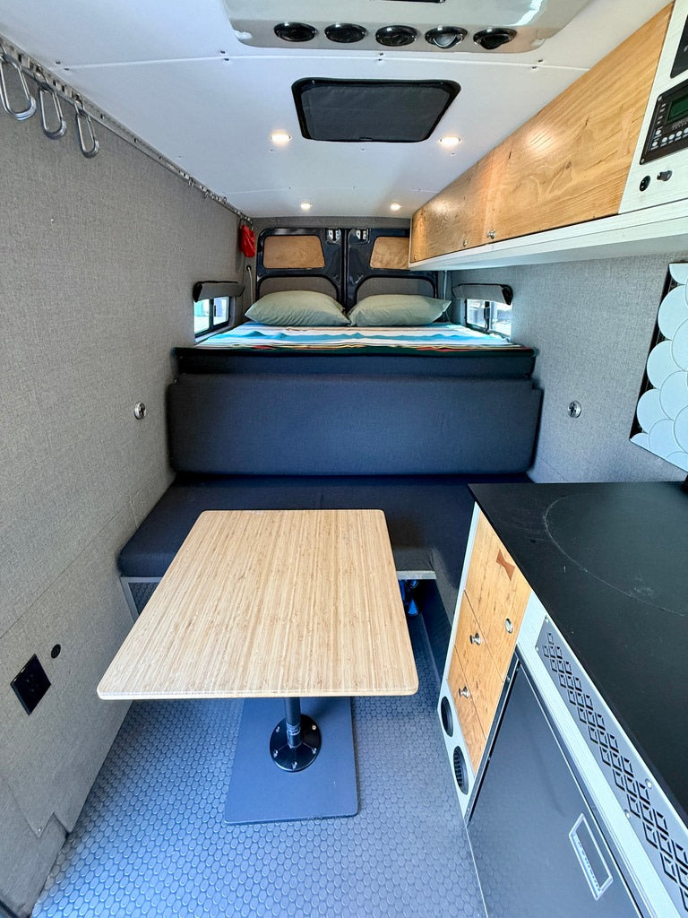 RV rental camper van interior. Enjoy a comfortable bed, dining table, and compact kitchen perfect for road trips.