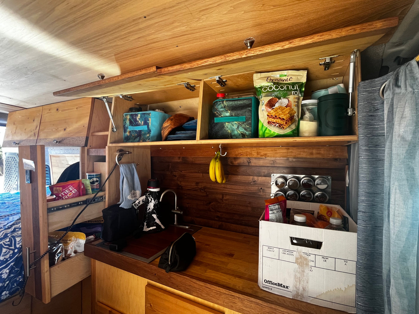 Inside an RV rental: Wooden kitchen with clever storage solutions, sink, and essentials for a comfortable mobile journey.