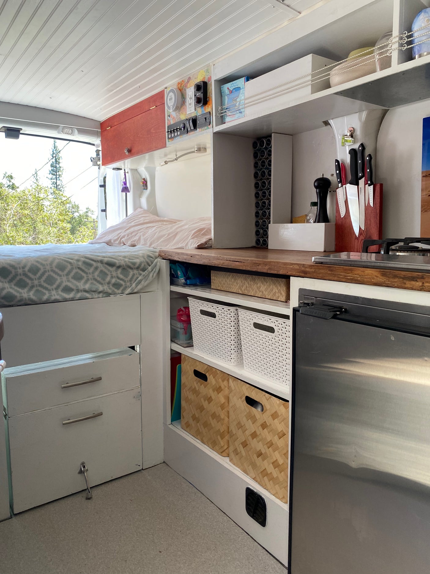 Spacious RV rental interior featuring a cozy bed, full kitchen with stove/fridge, and ample storage solutions.
