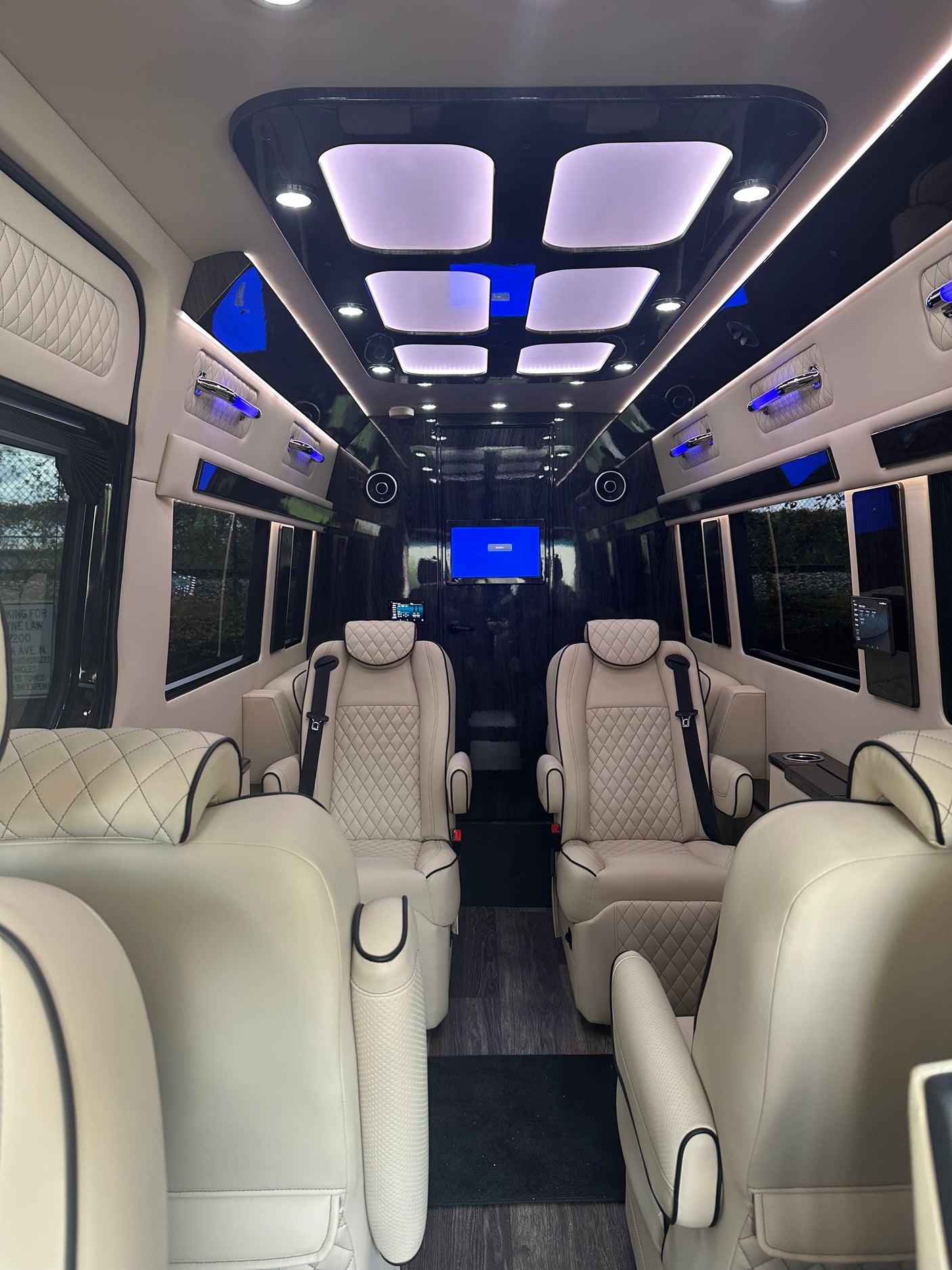 Luxury RV rental interior: spacious cabin with cream leather captain's chairs, custom lighting, and entertainment system.