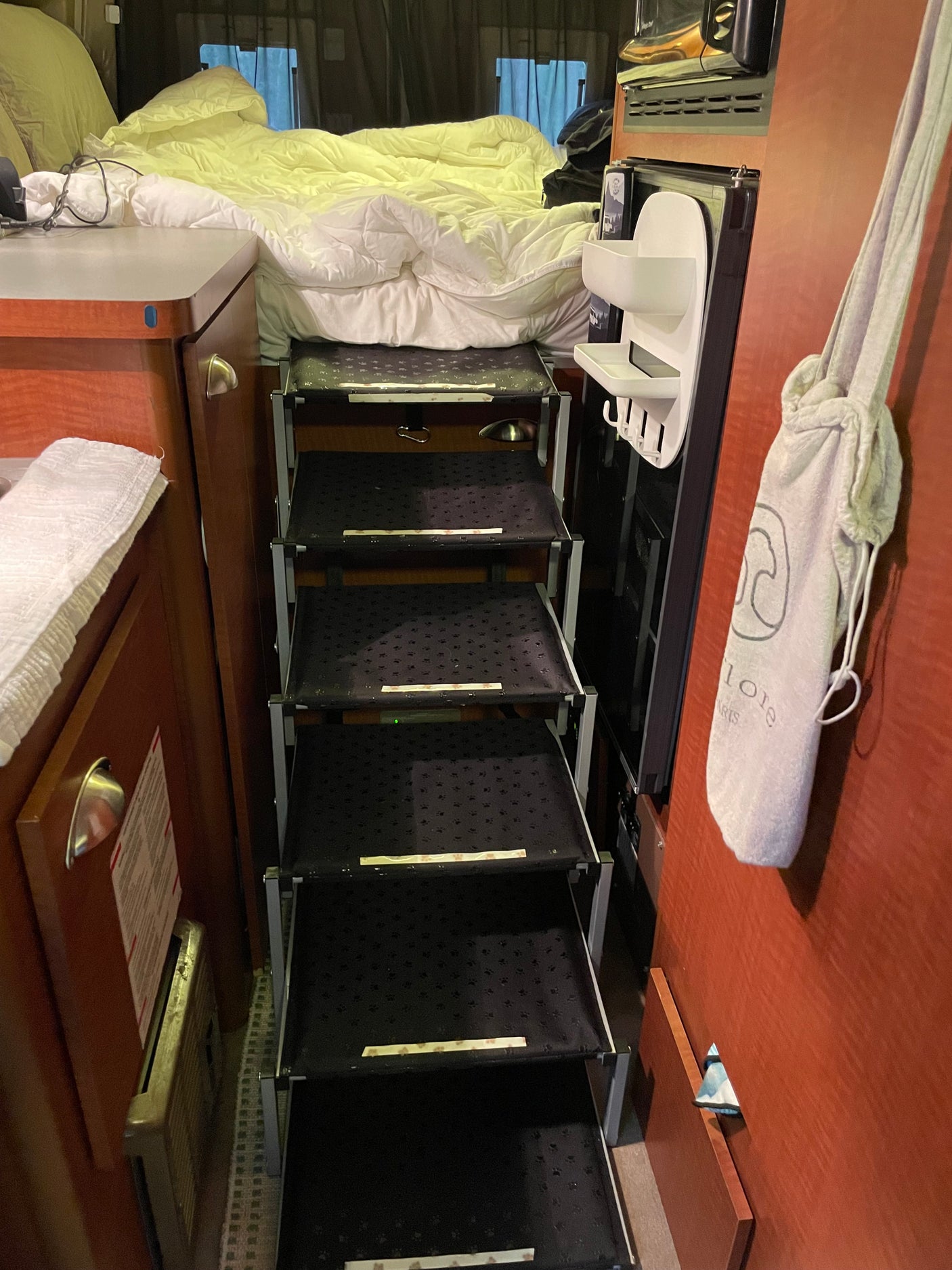 Cozy rv rental sleeping area with a bed and multi-tiered pet stairs (with paw prints). Thoughtful design for pets.