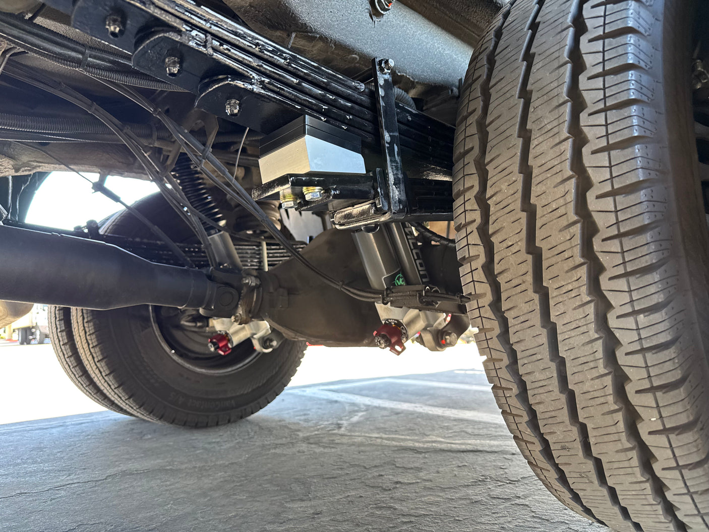 RV rental undercarriage: detailed view of heavy-duty rear suspension, incl. leaf springs, axle, and Falcon shocks. Vehicle mechanics insight.