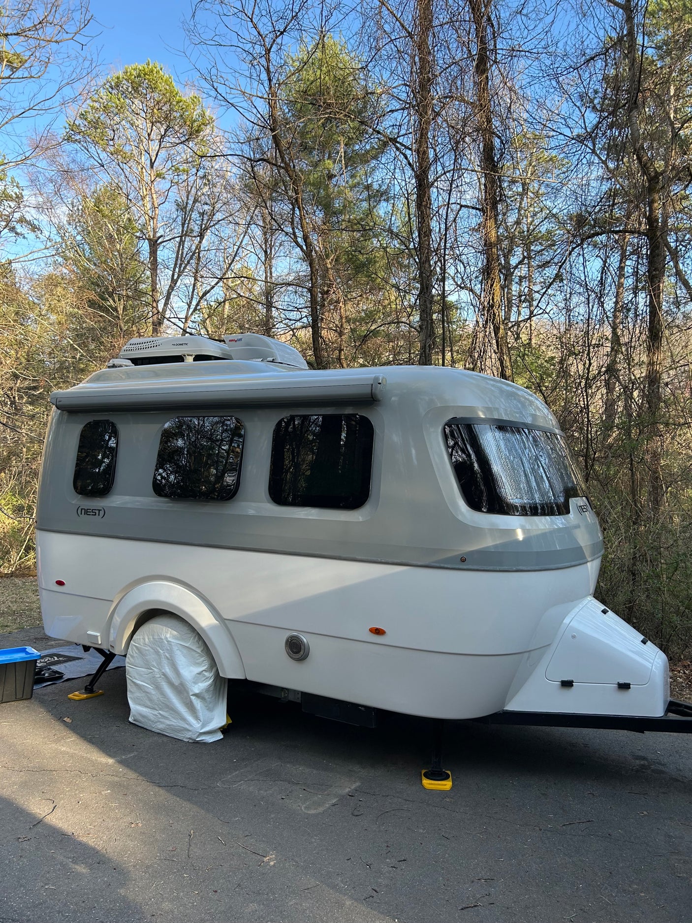 This Nest by Airstream travel trailer, an ideal rv rental, is set up at a wooded campsite, ready for an outdoor getaway.