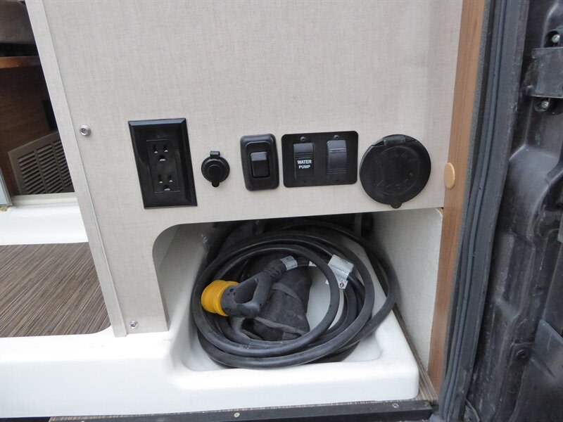 and overhead cabinets for a comfortable camper van experience.|RV rental interior with a cozy bed
