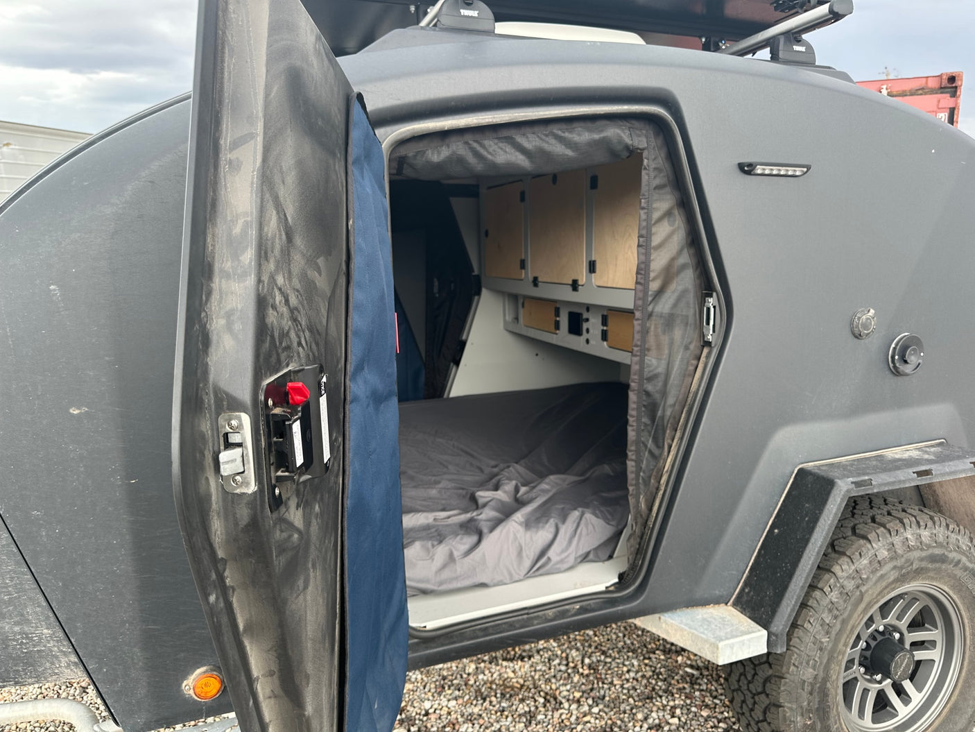 Inside this rugged RV rental: a comfy camper trailer bed and built-in storage.