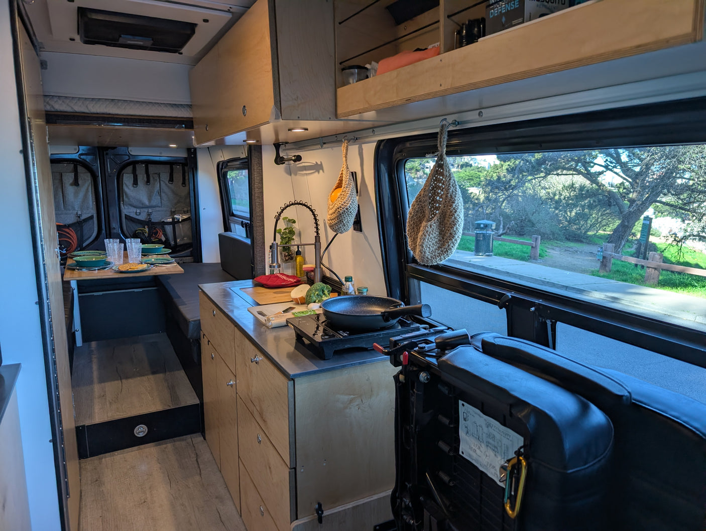 RV rental interior: a cozy campervan featuring a kitchen, dining area, bed, and outdoor views for comfortable travel.