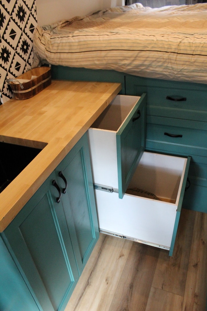 and two wall-mounted reading lights.|This RV rental interior showcases a cozy custom kitchenette with teal cabinets