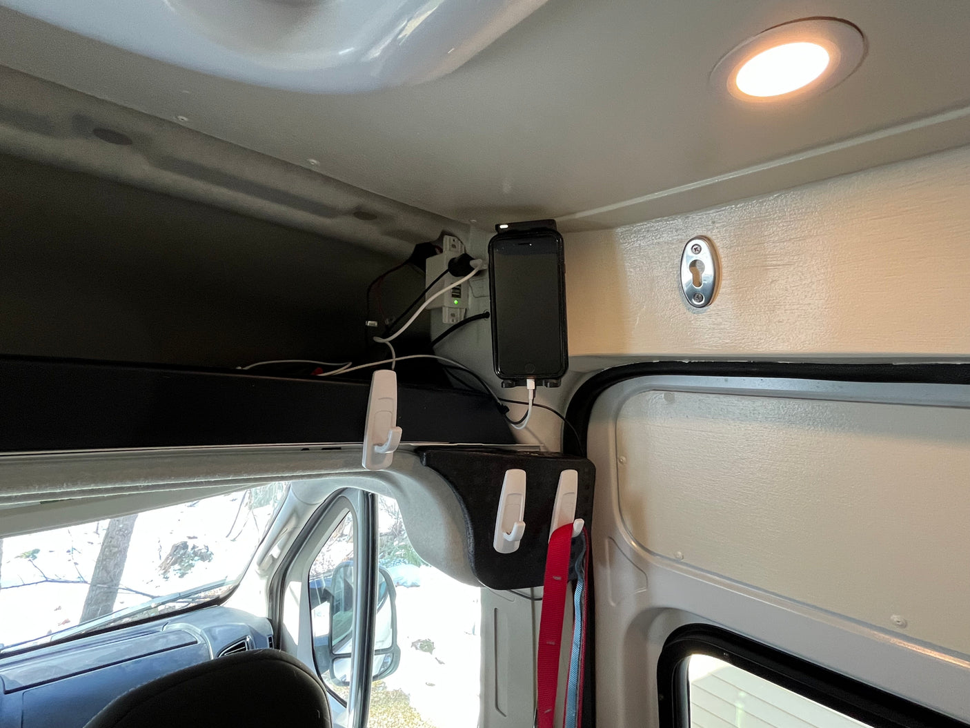 RV rental interior: Overhead storage, phone charging station, and organization hooks for mobile living in a camper van.