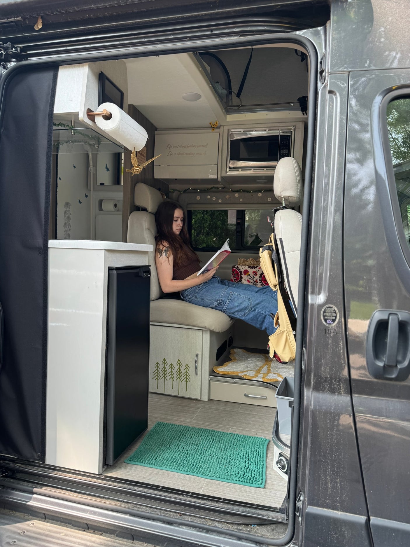Experience comfort in this rv rental: A woman reads in a cozy, well-appointed camper van.