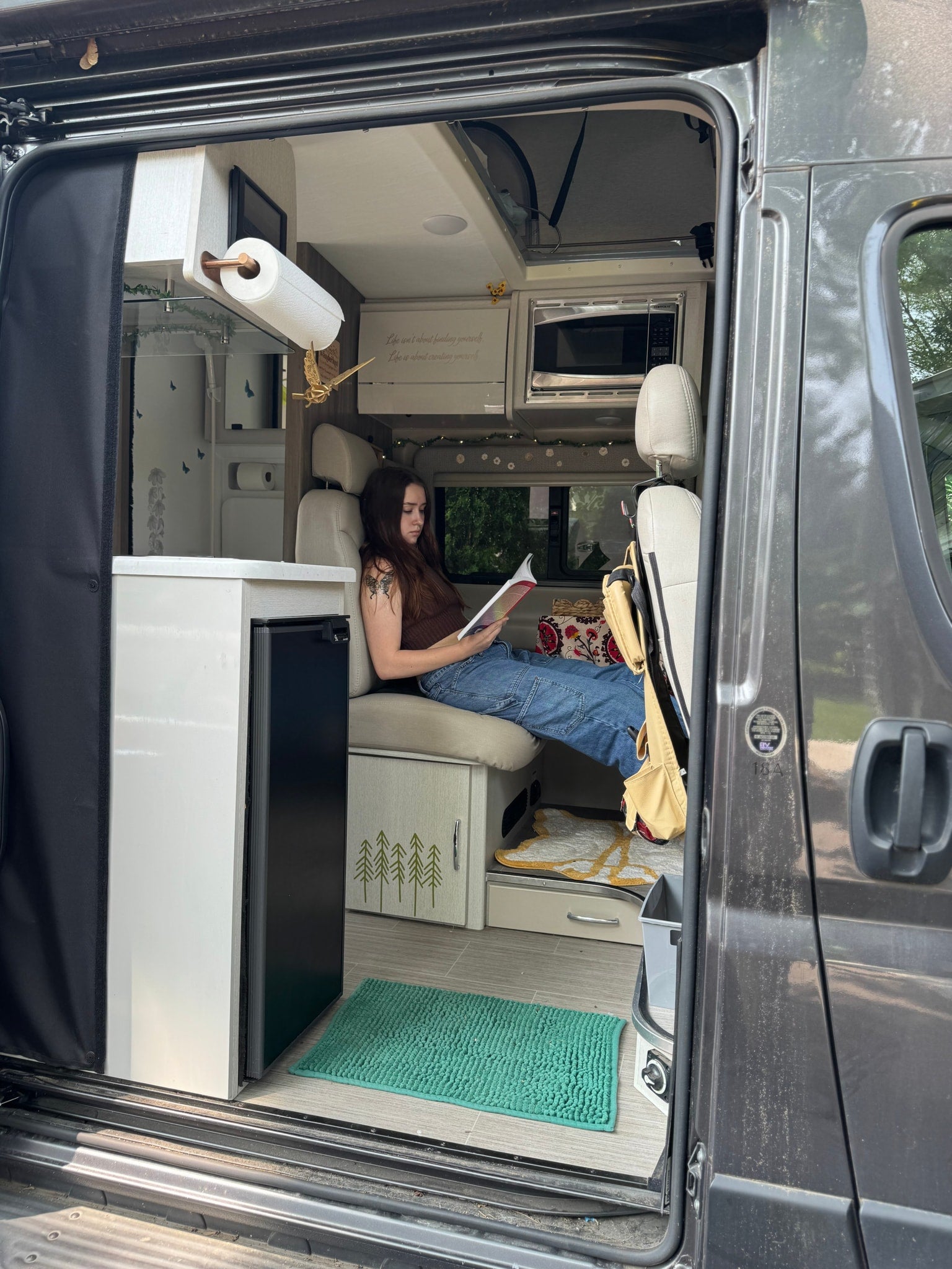 Experience comfort in this rv rental: A woman reads in a cozy, well-appointed camper van.