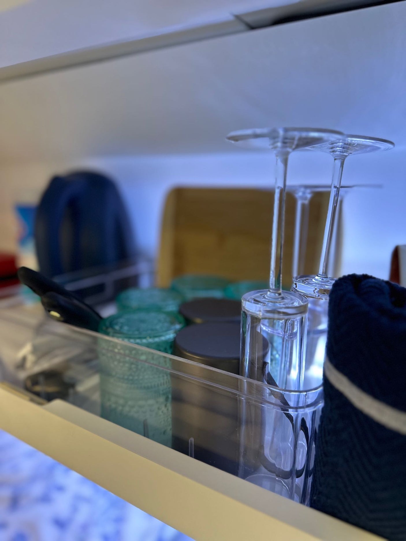 Inside an RV rental kitchen cabinet: inverted wine glasses, tumblers, and other essentials, neatly organized.