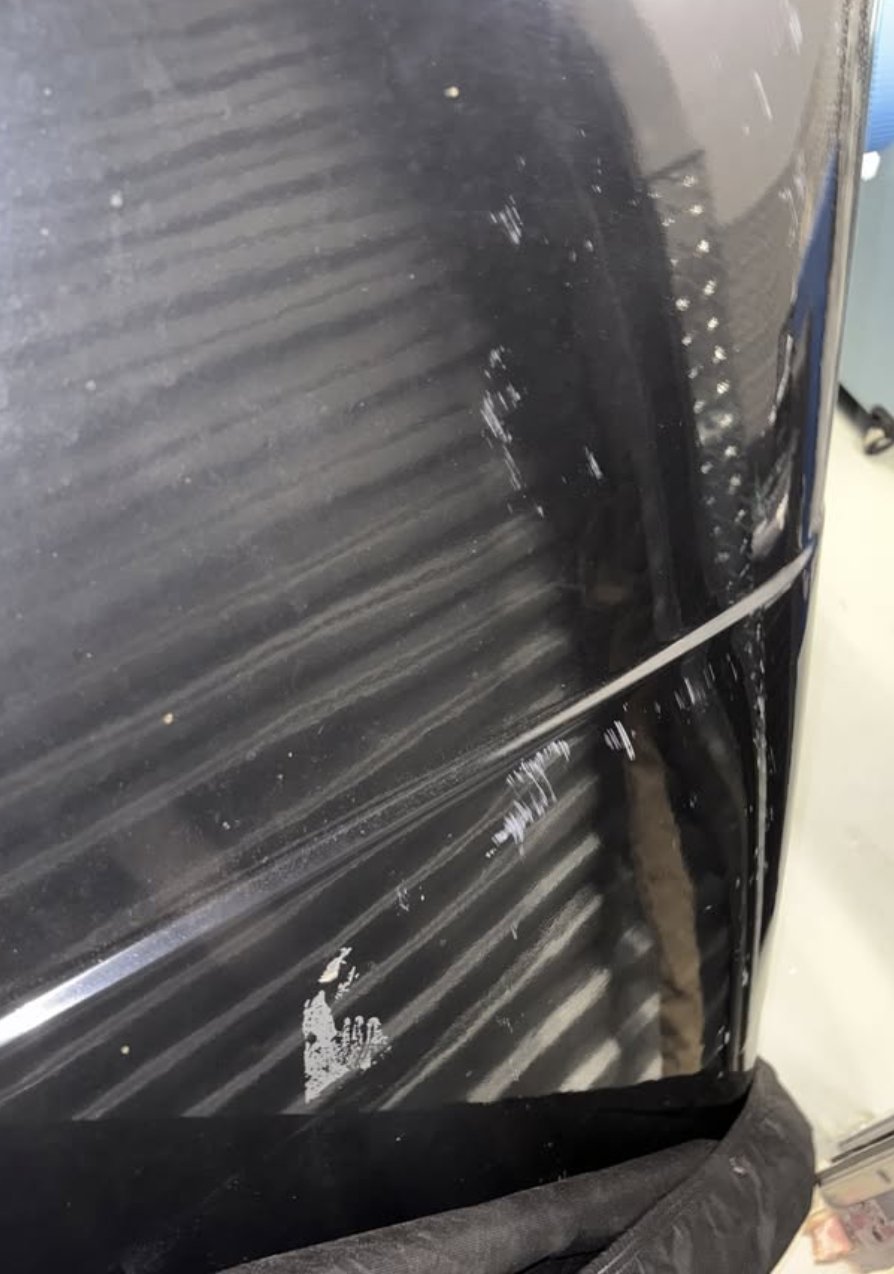 Detail of the light surface scratches on the top of the black hardshell described by the seller, shot close in under overhead light with the cover folded back — photo 4