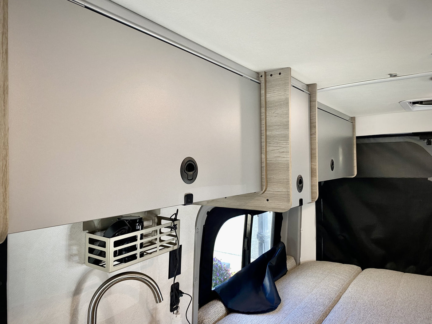 RV rental: Modern camper van interior featuring sleek overhead storage, a compact kitchenette, and plush sleeping area.