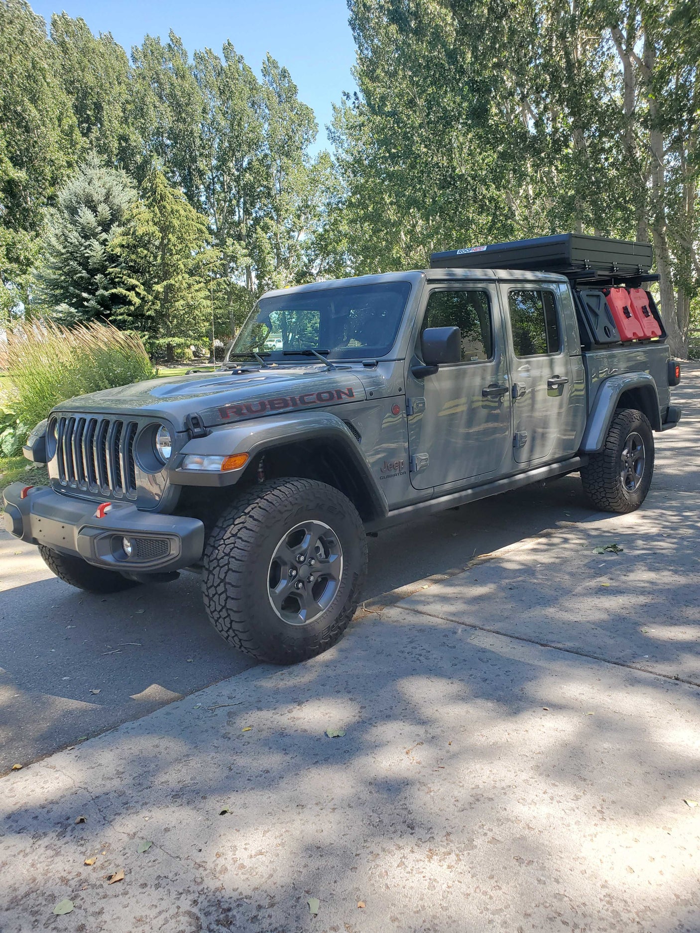 Gray Jeep Gladiator Rubicon with rooftop tent & fuel cans. An overland rig perfect for adventures, or a rugged rv rental option.