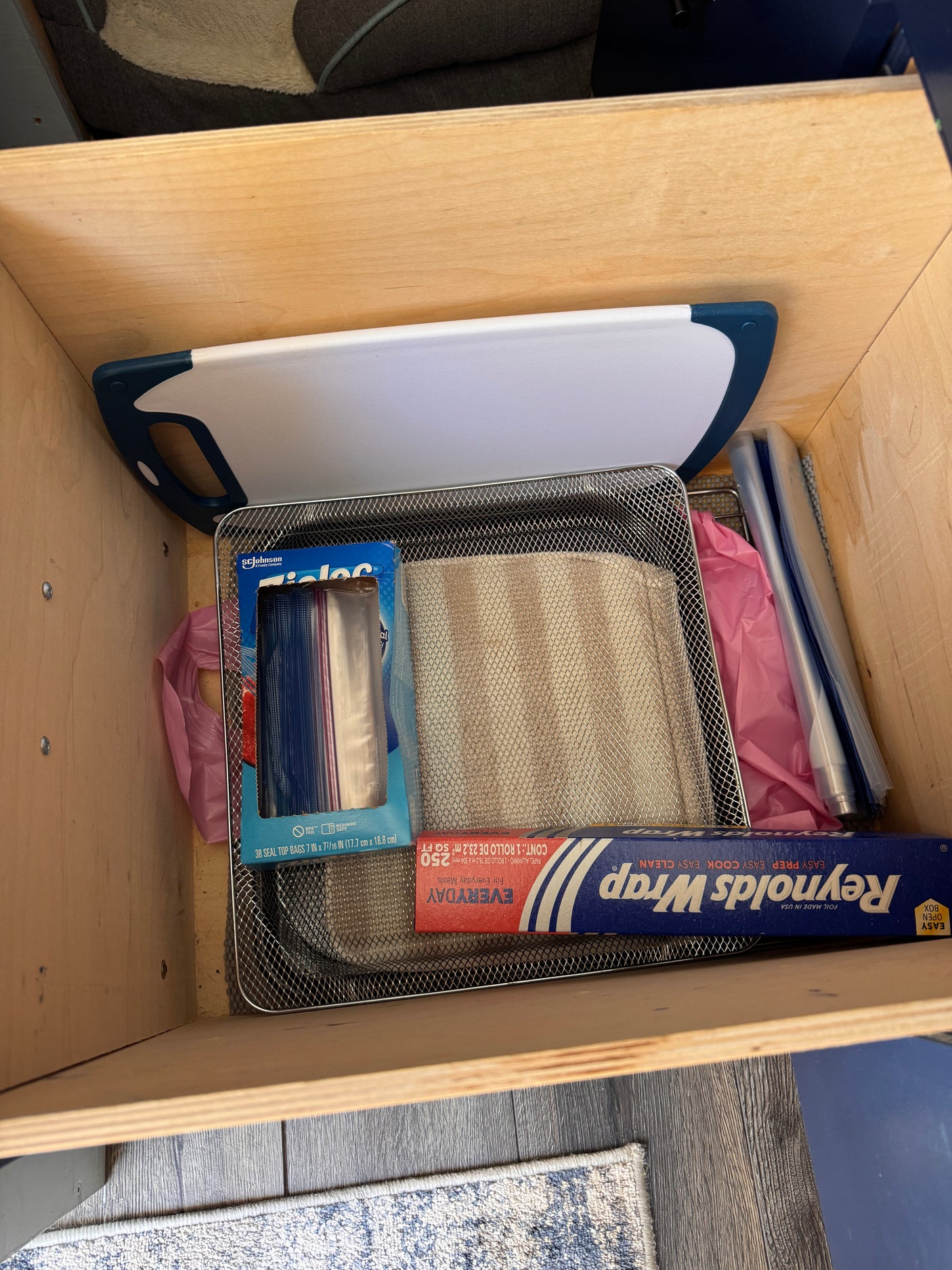 A well-organized RV rental kitchen drawer with a cutting board, Reynolds Wrap, and Ziploc bags for compact storage.