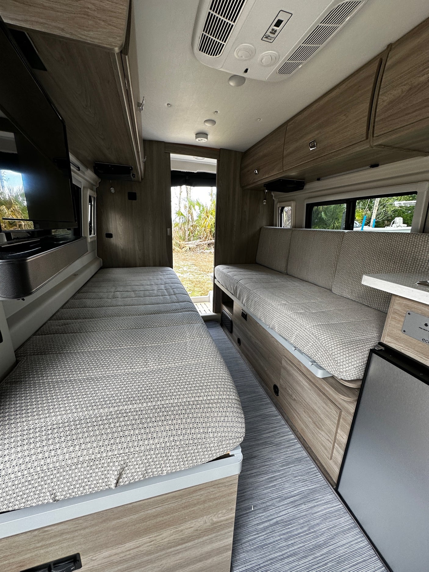 Spacious and modern RV rental interior featuring comfortable beds, wood cabinets, and large windows. Perfect for adventure.