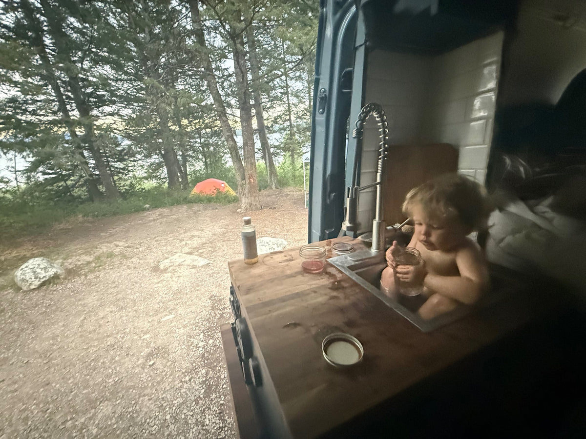 and a comfy passenger seat.|This rv rental features a modern van interior with a custom kitchen — photo 11