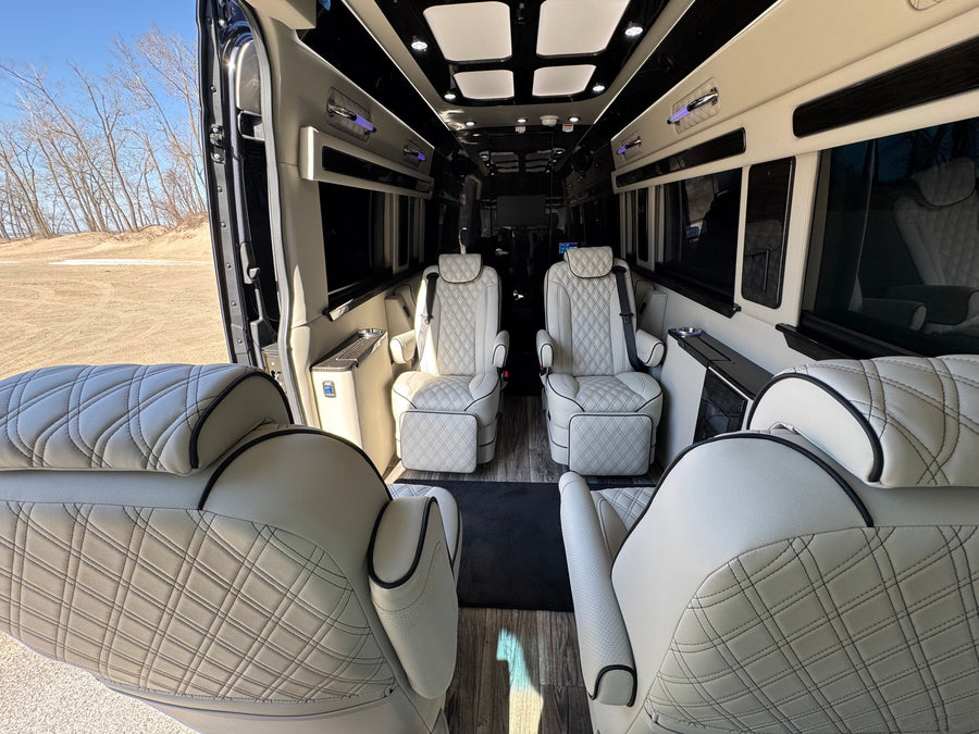 diamond-stitched white captain's chairs with black piping and wood-look flooring.|Plush RV rental interior with light leather quilted captain's chairs