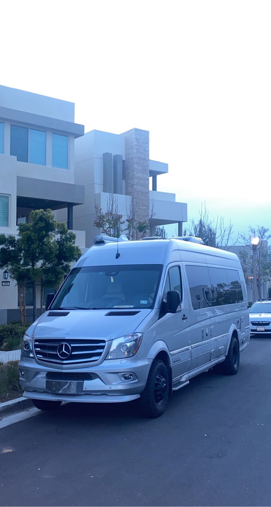 Silver Mercedes-Benz Sprinter RV rental van parked on a street, with modern residential buildings in the background. — photo 16