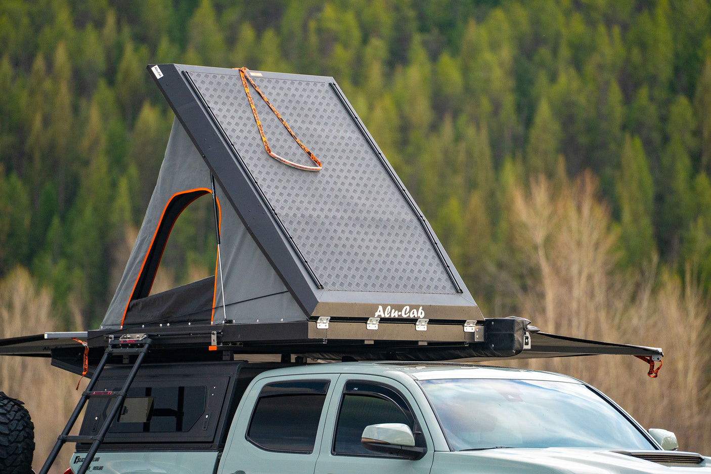 and pillows for your adventure.|Sage green Tacoma with rooftop tent & camping setup on riverbank. An ideal rig for adventure travel