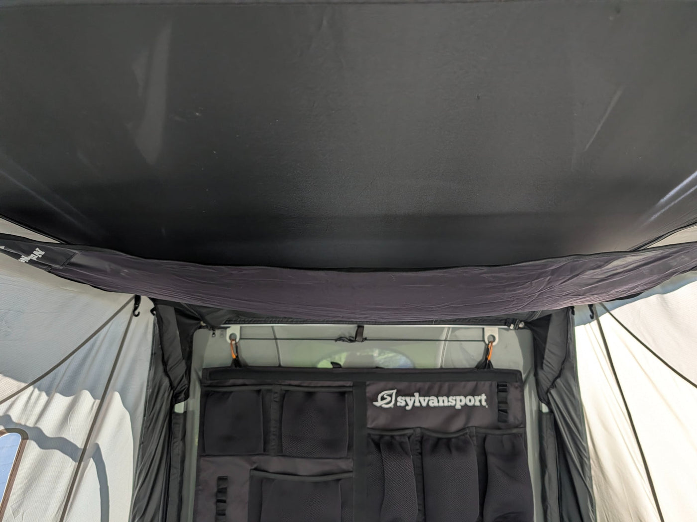 and bright green fabrics.|RV rental interior: SylvanSport pop-up camper's sleeping area with mattress and windows looking out onto a neighborhood.|Interior of a SylvanSport pop-up camper — photo 19