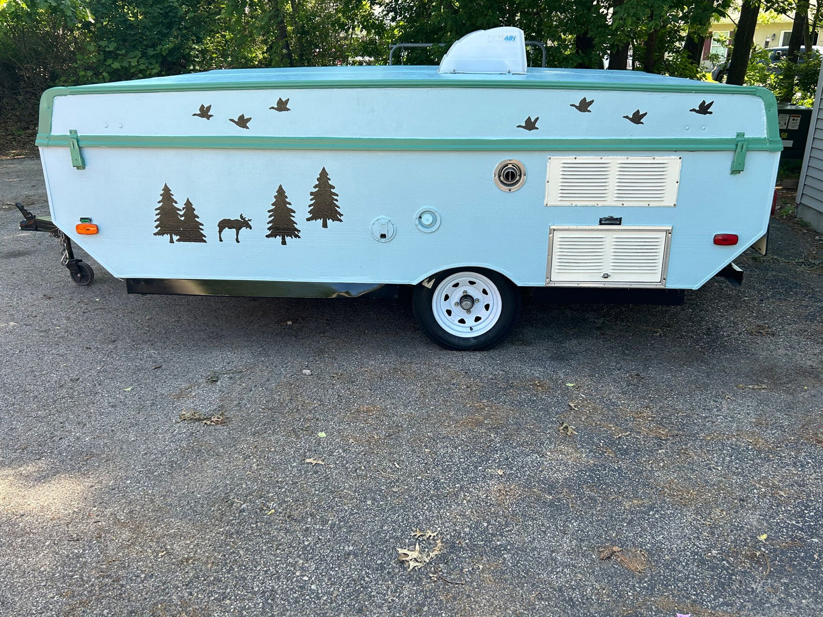 Light blue pop-up camper with nature decals (trees