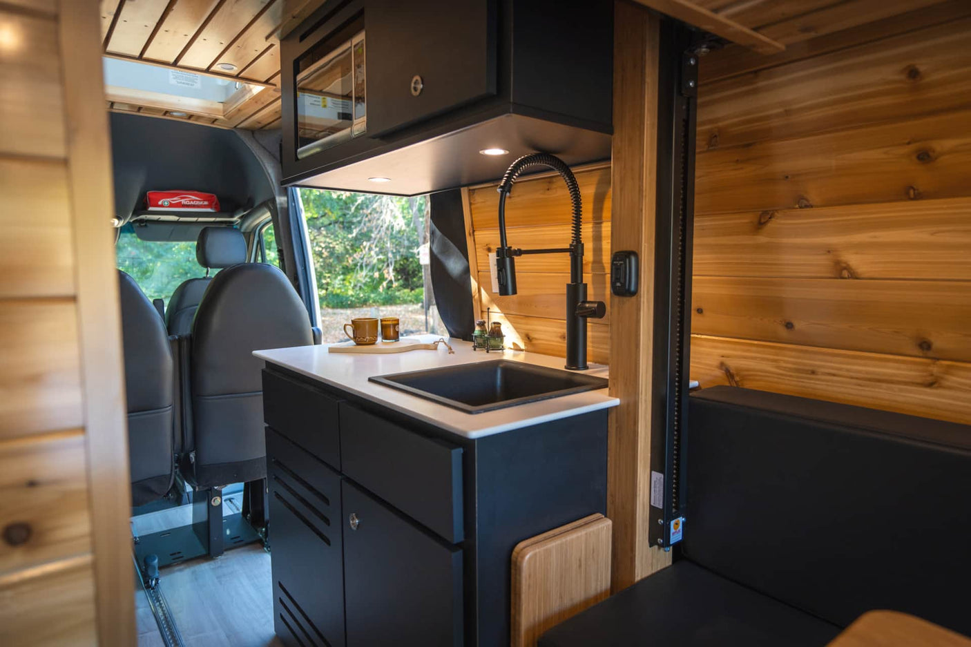 parked on a leafy path in autumn woods.|View inside a custom RV rental van: wooden interior