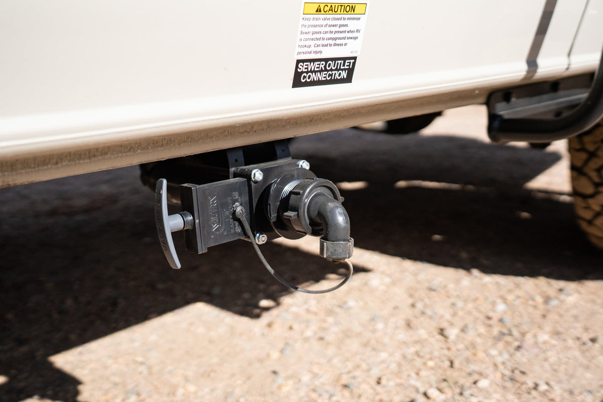 This RV rental's sewer outlet connection with drain valve and caution label ensures proper waste disposal and safety during use. — photo 16