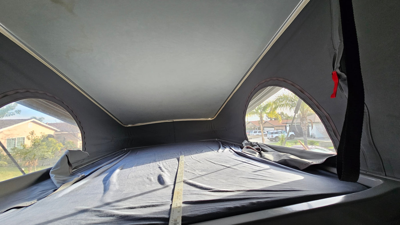 Inside an RV rental's pop-up tent, showing the bed area and side windows with outside views. — photo 8