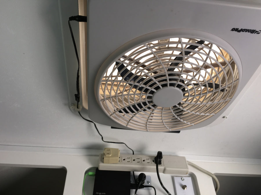 RV rental ceiling fan, power strip, and electronics are seen, providing comfort and connectivity in a compact space.