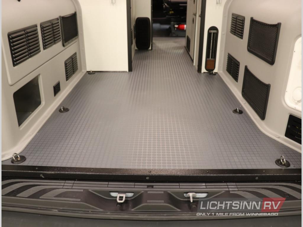 Explore the spacious rear of this RV rental van, featuring a textured non-slip floor, side vents, and cargo tie-downs.