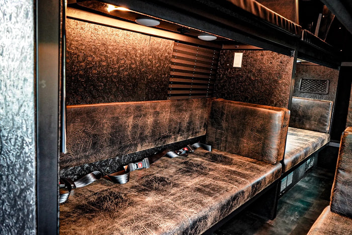 and charging outlets for comfort.|This luxury RV rental interior boasts plush seating and dual screens playing movies/Netflix for ultimate travel comfort.|Custom RV rental interior with distressed leather seating & seatbelts. Luxury transport for your next adventure.|Luxurious custom RV rental interior with distressed brown seating