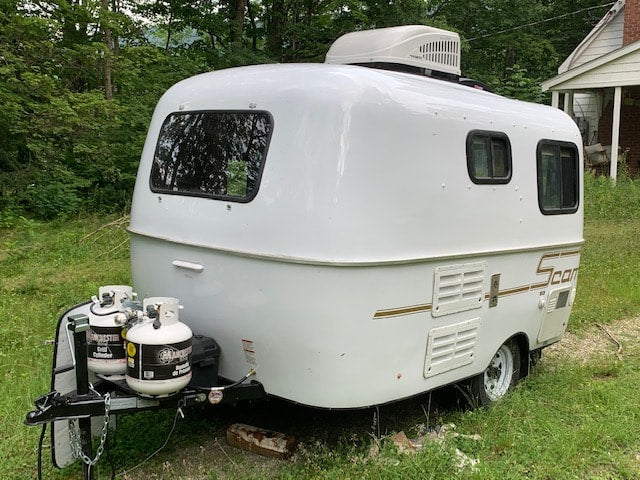complete with AC and spare tire.|White Scamp travel trailer with dual propane tanks and rooftop AC