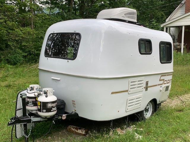 complete with AC and spare tire.|White Scamp travel trailer with dual propane tanks and rooftop AC