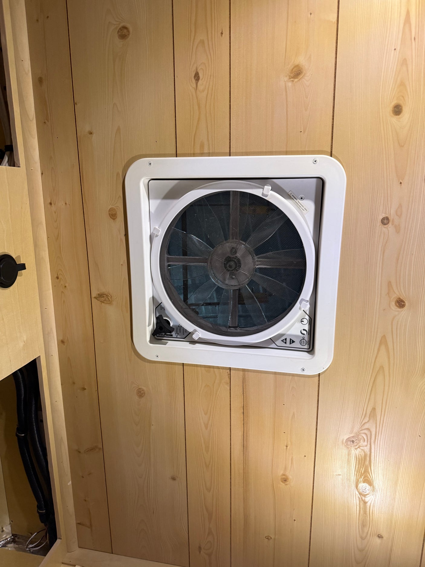 Inside an rv rental: a white Maxx Fan installed in knotty pine wood paneling, offering essential ventilation.