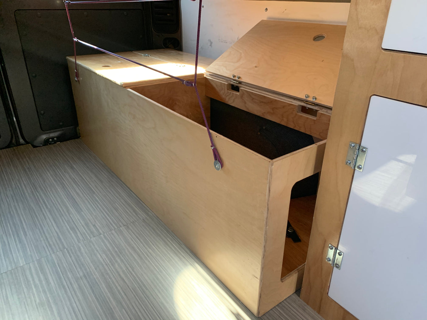 This RV rental interior features custom plywood storage, including an open bed/bench area and hinged compartments.