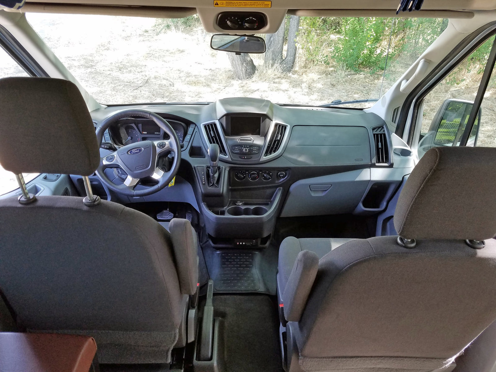 Ford Transit van interior: dashboard, steering wheel, and front seats. Perfect for your next RV rental adventure!