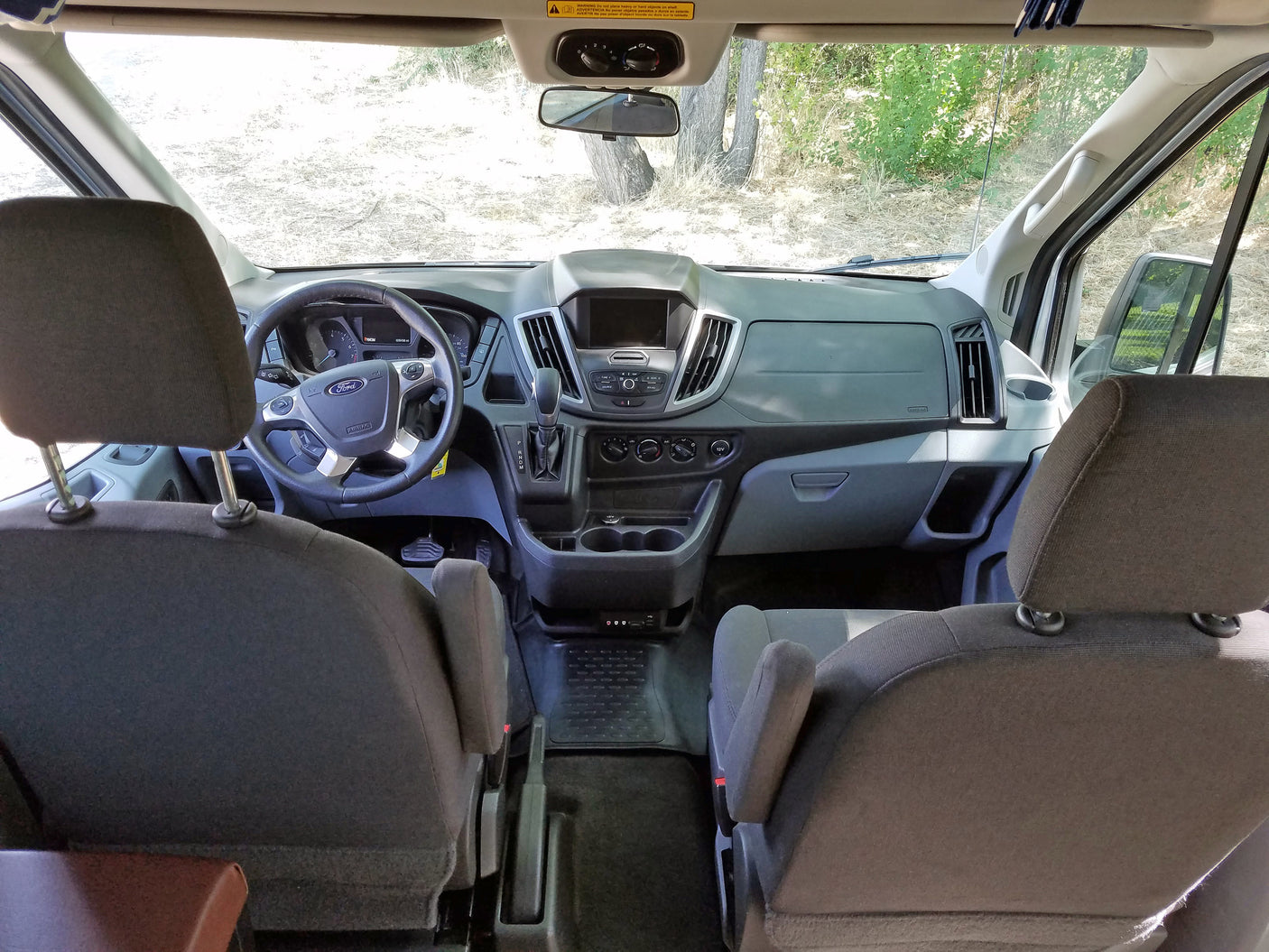 Ford Transit van interior: dashboard, steering wheel, and front seats. Perfect for your next RV rental adventure!