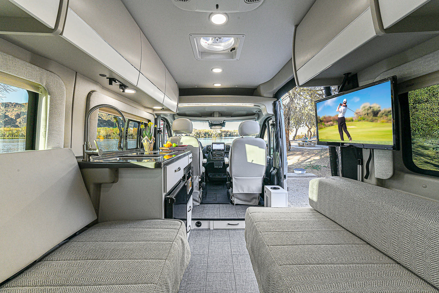 Spacious rv rental interior with kitchen, comfy seating, and TV. Perfect for road trips and relaxation.