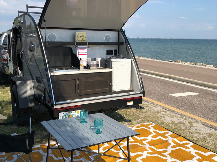 FreeSolo teardrop RV rental: Open rear kitchen (stove, sink, fridge), table & mat offer waterfront camping.