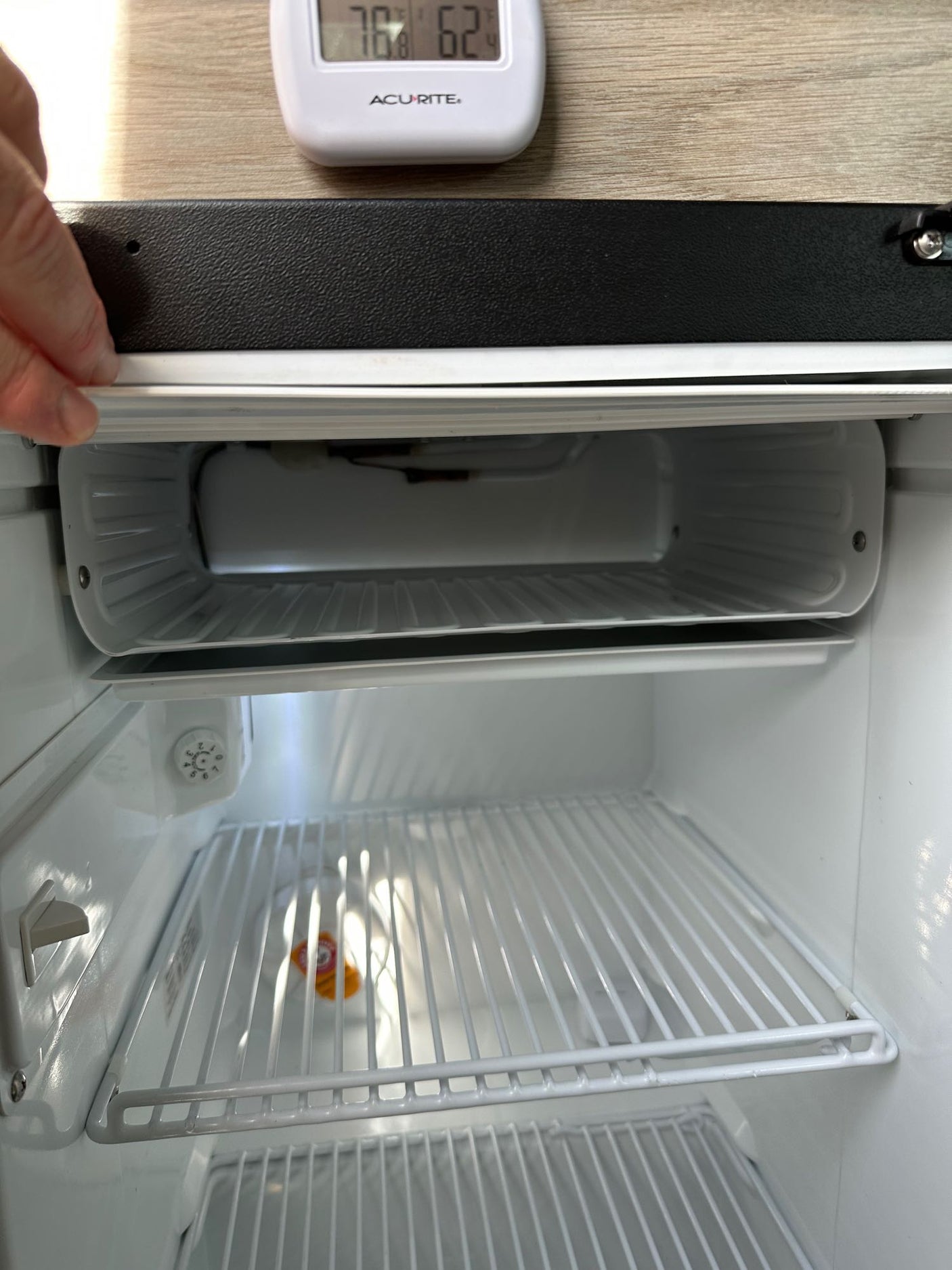 Inside a clean, empty compact refrigerator, typical for an RV rental. Features include a top freezer compartment and wire shelves.