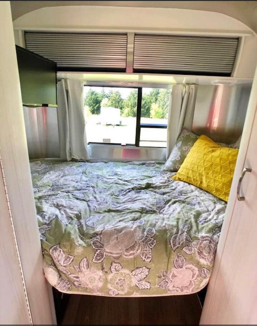 Cozy RV rental bedroom with a floral bedspread, TV, and large window. Perfect for travel adventures.