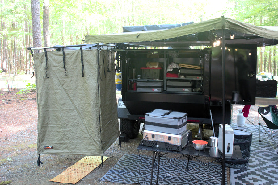 Campsite ready! This overlanding trailer, with an awning, shower tent, and camp gear, is ideal for an RV rental.