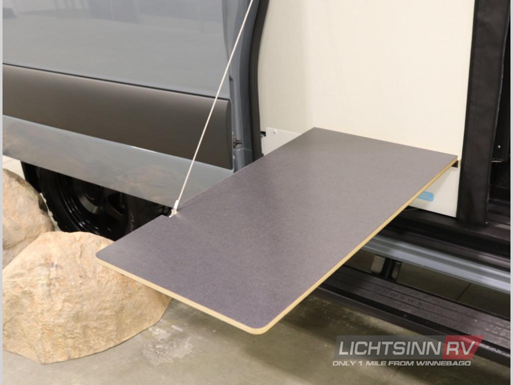 RV rental camper van's exterior pull-out table, suspended by a cord, for convenient outdoor use.