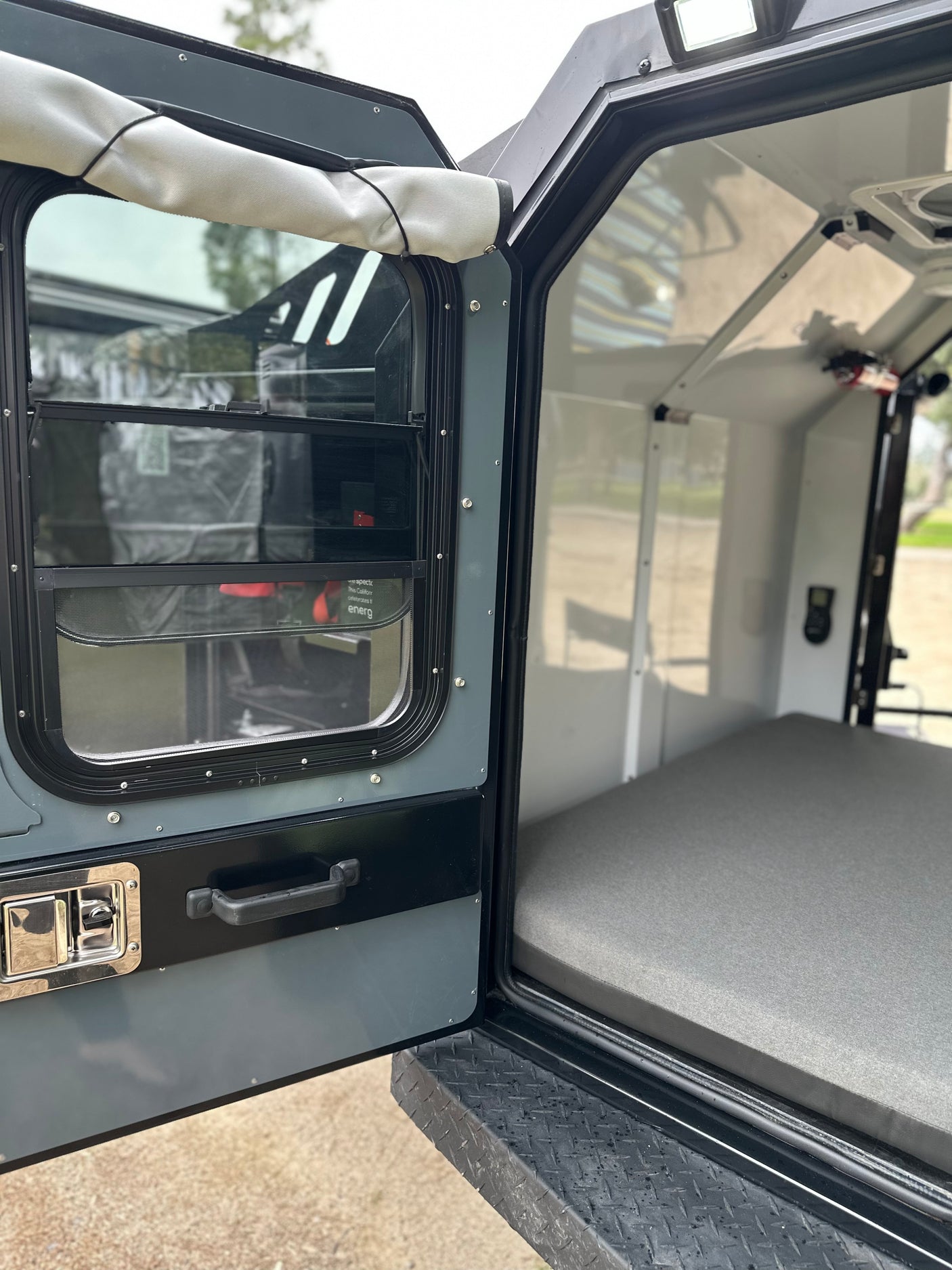 Inside an RV rental: View from the open side door of a camper, revealing a comfortable sleeping area and interior.