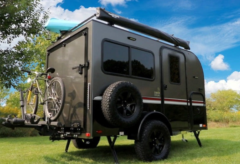 Adventure-ready RV rental: a compact travel trailer with bikes & kayak, set up for outdoor exploration.