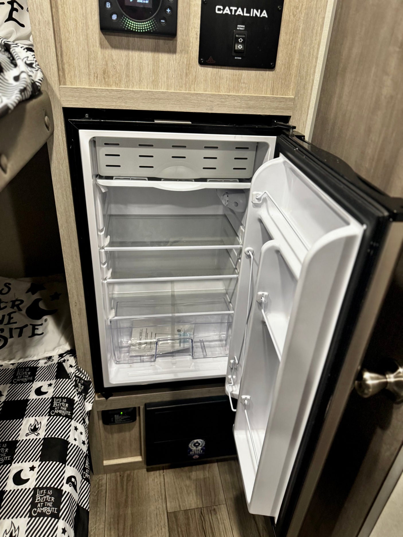 RV rental interior features a clean, empty fridge, bunk bed, and Catalina control panel. Perfect for camping trips.